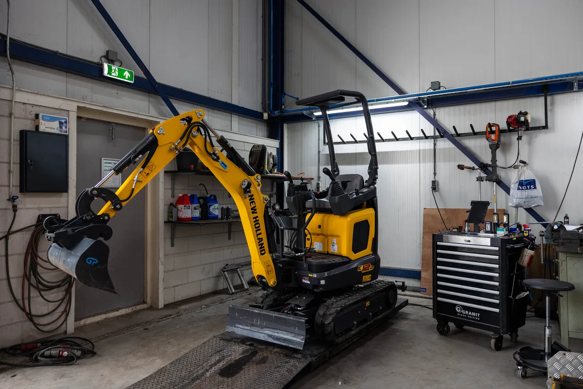 Gele New Holland Construction minigraver in de werkplaats van Voets Hazerswoude